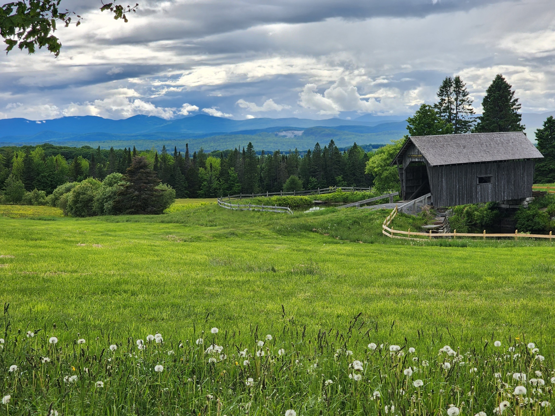Vermont covered bridge and green meadow with mountain backdrop